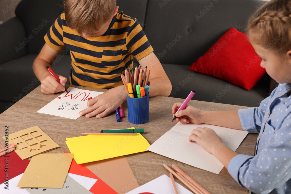 Children making beautiful greeting cards at table indoors Children making beautiful greeting cards at table indoors
