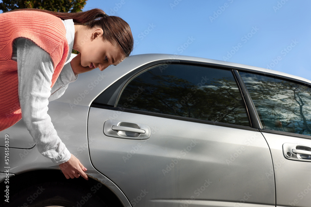 Stressed woman near car with scratch outdoors Stressed woman near car with scratch outdoors