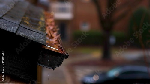 rain water rushing down the roof into the gutter clogged with fallen leaves