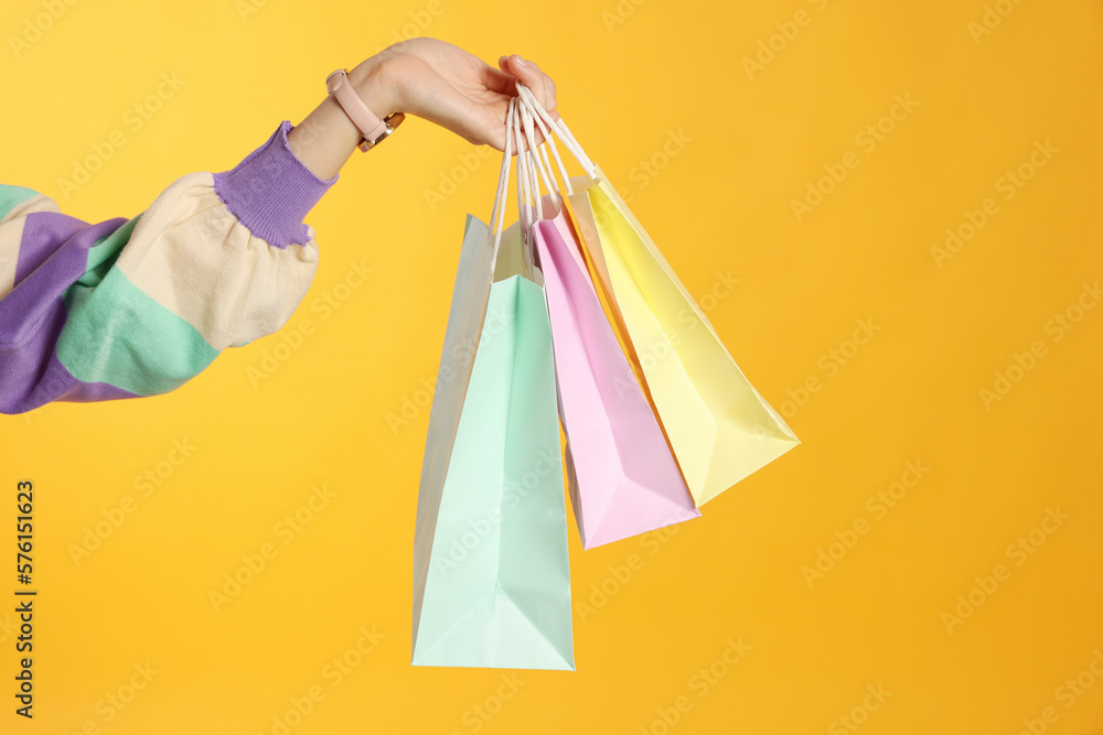 Woman holding shopping bags on yellow background, closeup. Big sale