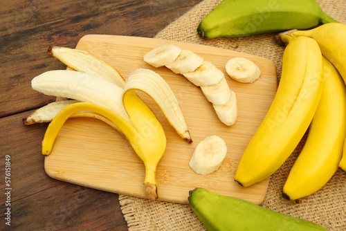 Whole and cut bananas on wooden table
