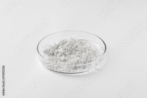 Petri dish with calcium carbonate powder on white background