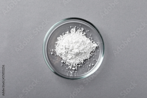 Petri dish with calcium carbonate powder on grey table, top view