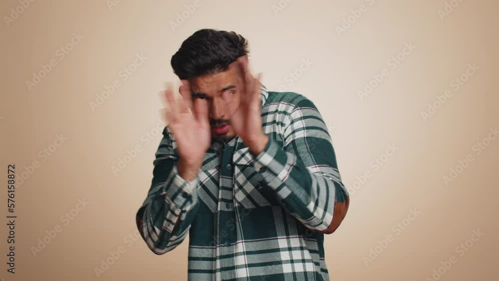 Stressed depressed indian man terrified about danger problems, suffering phobia, anxiety disorder, expresses fear, waving no, insecure, stress, panic. Hindu guy isolated on beige studio background Stressed depressed indian man terrified about danger problems, suffering phobia, anxiety disorder, expresses fear, waving no, insecure, stress, panic. Hindu guy isolated on beige studio background