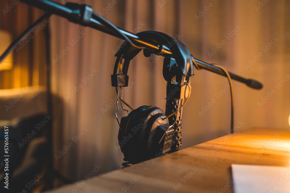 A close up shot of podcast headphones hanging on microphone stand in home podcast studio