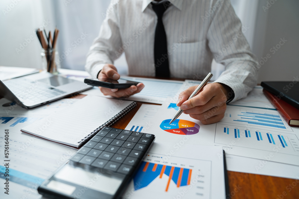 Young Asian businessmen sit analyzing data at the desk and pointing at charts and graphs comparing management practices. Young Asian businessmen sit analyzing data at the desk and pointing at charts and graphs comparing management practices.