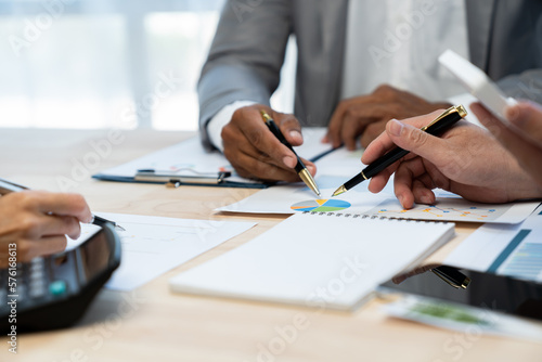 Group of Asian businessmen brainstorming numbers in company financial documents. Financial analyst pointing to data graph to check company with finance and accounting department meeting concept.