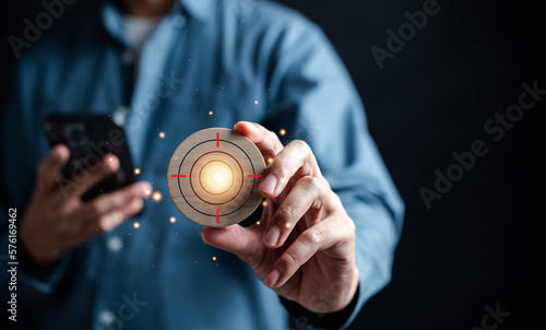 Businessman hand holding target objective icon which for planning development leadership and customer target group concept. © Kiattisak