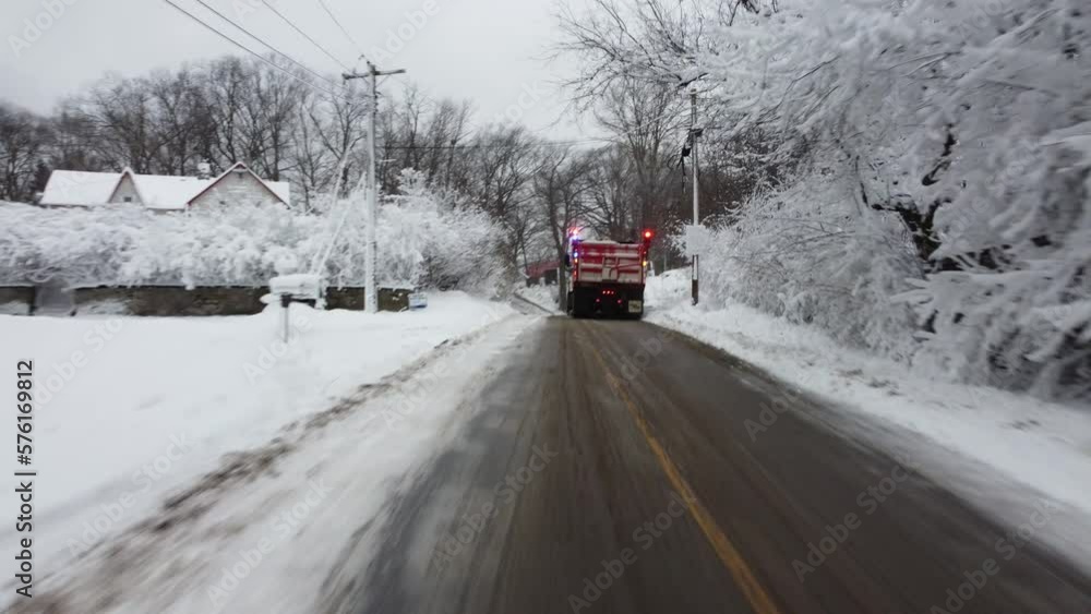 Aerial view following a plow truck through a twisty hilly road after a heavy snow storm near a cemetary Aerial view following a plow truck through a twisty hilly road after a heavy snow storm near a cemetary