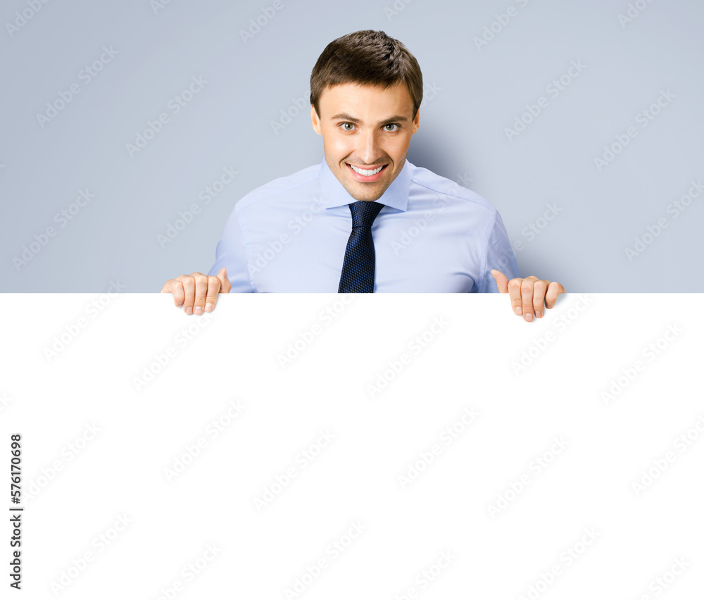 Portrait image of business man professional bank manager in confident cloth. Businessman stand behind hang over empty white banner signboard with copy space. Isolated on grey gray background Portrait image of business man professional bank manager in confident cloth. Businessman stand behind hang over empty white banner signboard with copy space. Isolated on grey gray background