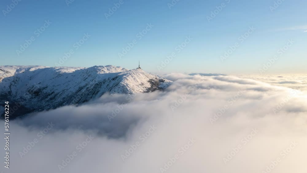 Drone shot just above inversion clouds showing a winter landscape with mountains in Bergen, Norway Drone shot just above inversion clouds showing a winter landscape with mountains in Bergen, Norway