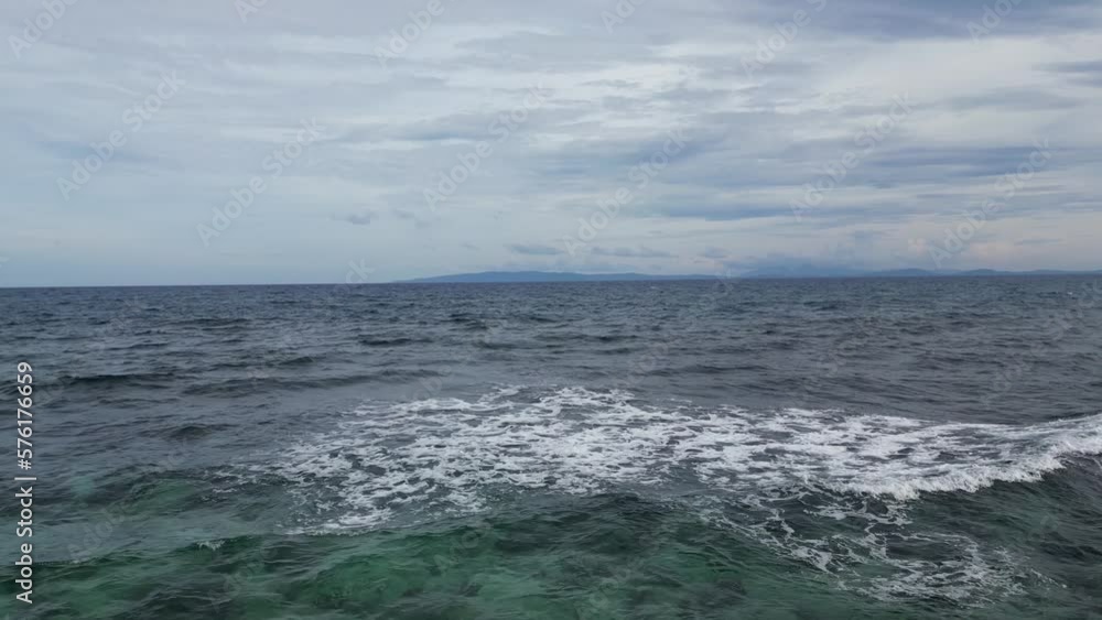 Aerial Drone Shot of foamy Waves crashing on Reef in middle of vast ocean with Cloudy Sky in background. Aerial Drone Shot of foamy Waves crashing on Reef in middle of vast ocean with Cloudy Sky in background.