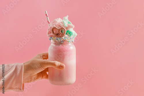 Fotografia Feminine hand holding a glass jar with a milkshake topped with cotton candy