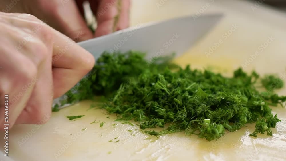 Hands of housewife cutting fresh green dill with knife Hands of housewife cutting fresh green dill with knife