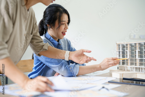 Concept of engineering consulting, Two female engineers pointing and explaining model of building