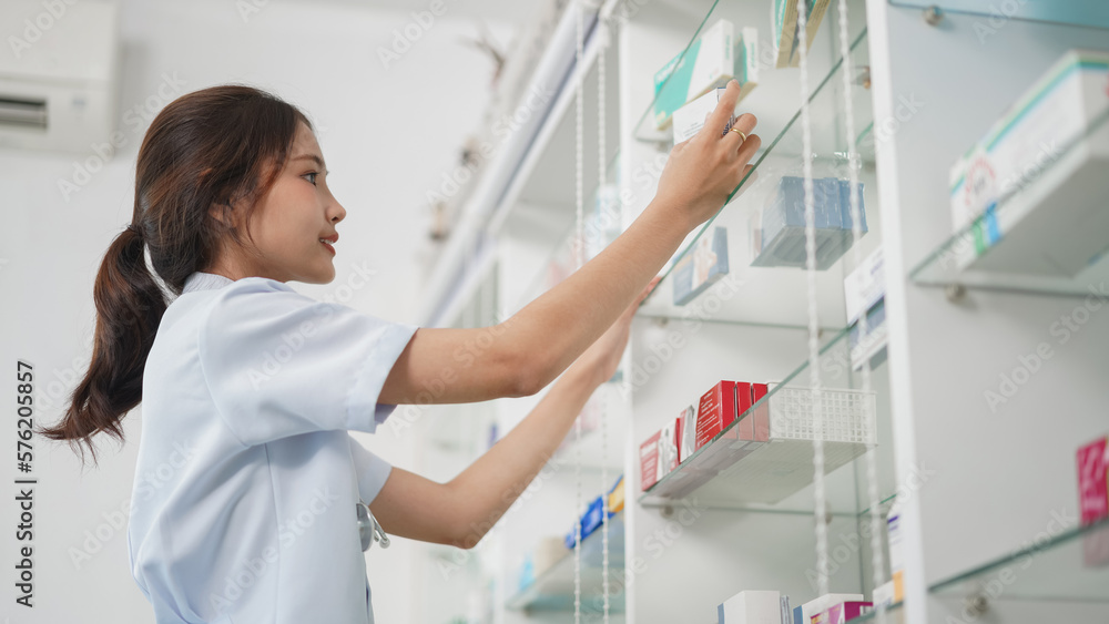 Medicine and health concept, Female pharmacist is checking medicine boxes on shelves in drugstore