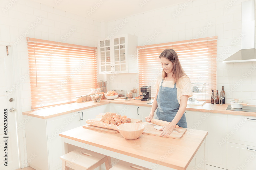 young woman work with wooden roller pin making sweet pie or pastry dough in kitchen, happy millennial female loving cooking. warm tone. young woman work with wooden roller pin making sweet pie or pastry dough in kitchen, happy millennial female loving cooking. warm tone.