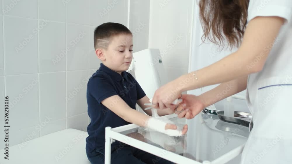 the boy is bandaging his hand in the medical office the boy is bandaging his hand in the medical office