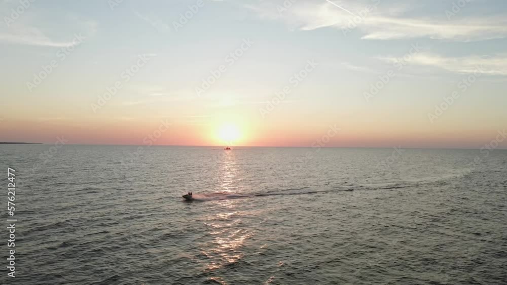 Leisure activity, jet skiing on the sea water in golden orange sunset, aerial view Leisure activity, jet skiing on the sea water in golden orange sunset, aerial view