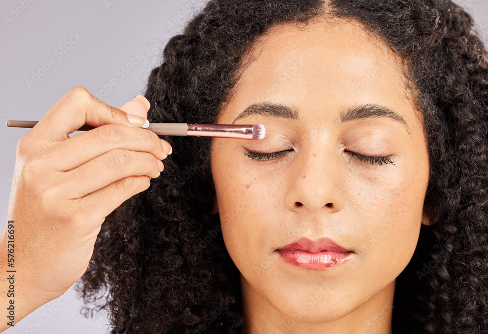 Obraz premium Face, makeup and black woman with eyeshadow brush in studio isolated on a gray background. Eyes closed, cosmetics and young female model with facial tool for beauty aesthetics, skincare and wellness.