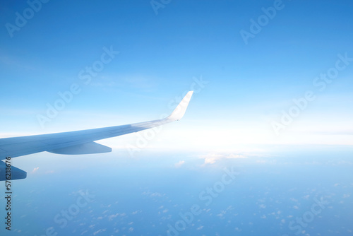Aircraft wing flying above the beautiful clouds with sunlight in the morning. Traveling concept. Wing of an aircraft
