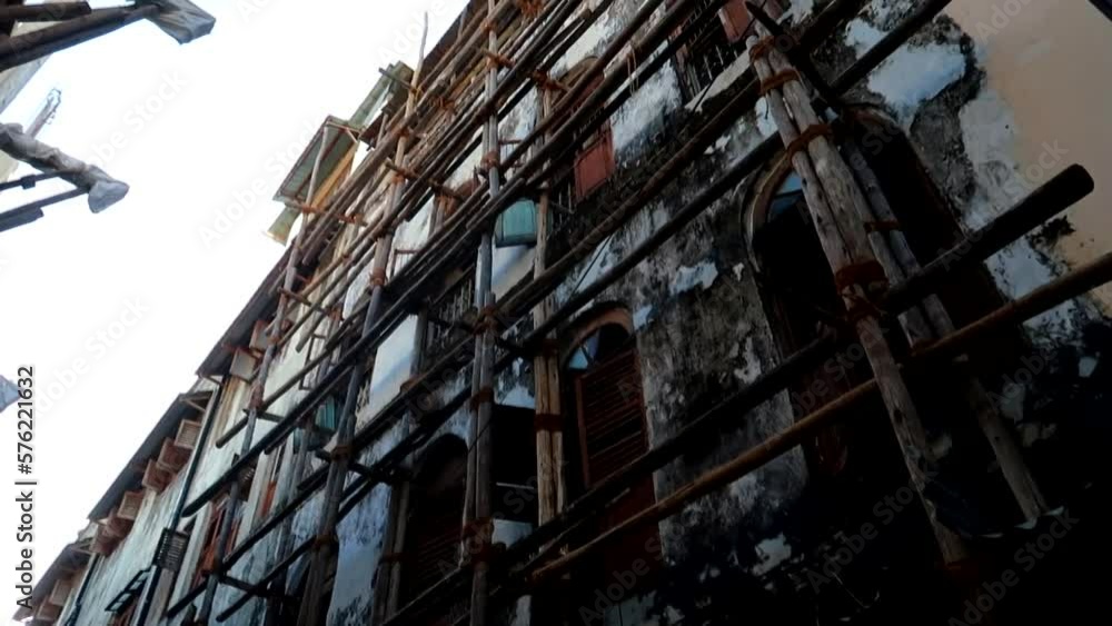 Tilting shot of a rundown building in Zanzibar undergoing repairs with wooden scaffolding Tilting shot of a rundown building in Zanzibar undergoing repairs with wooden scaffolding