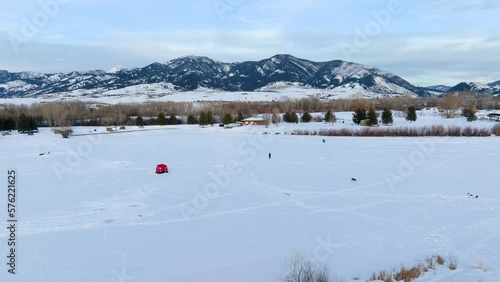 Boseman Montana Aerial flythrough over snowy suburban park at golden hour, 4k drone over ice fishermen and sledders with mountain backdrop photo