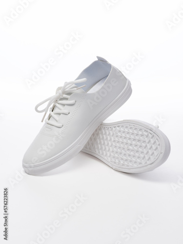 Pair of leather sport footwear on a white background. Isolated white sneakers with shadow. The shoes are stacked on top of each other