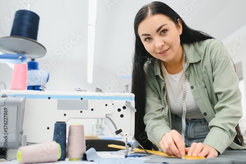 Beautiful young woman sewing clothes with sewing machine.