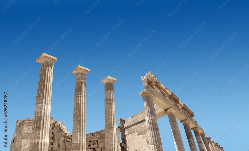 Ancient Greek antique temple facade stone ruins and columns against blue sky