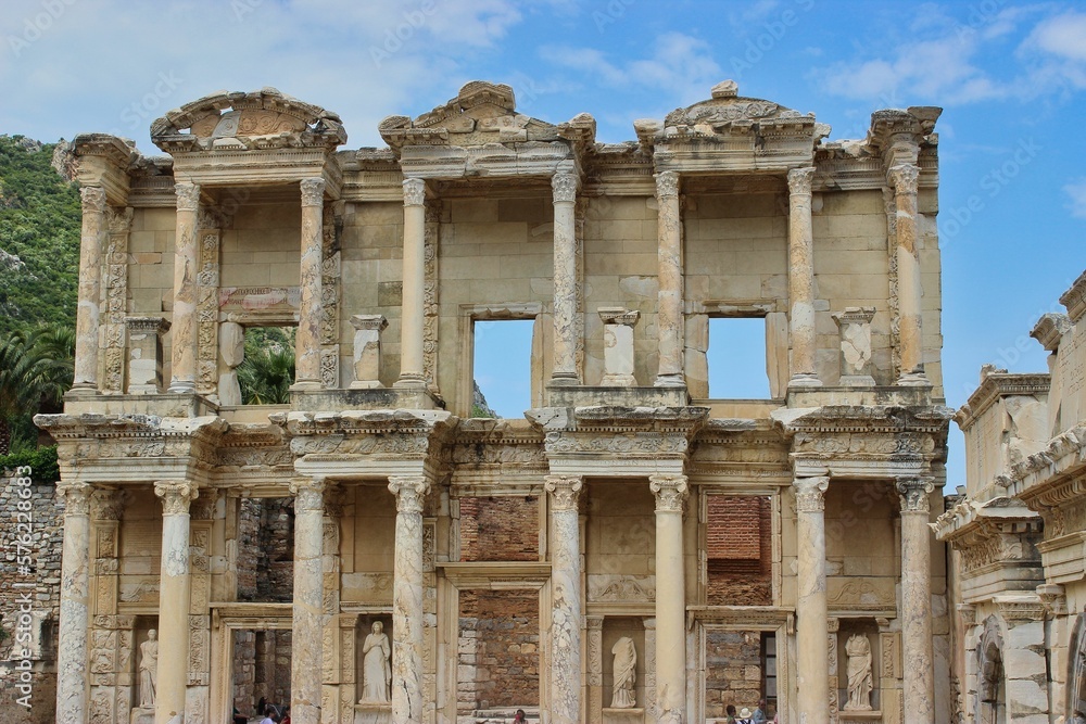 Front view of the ruins of a library in Ephesus Ancient City in Turkey against a bright blue sky.
