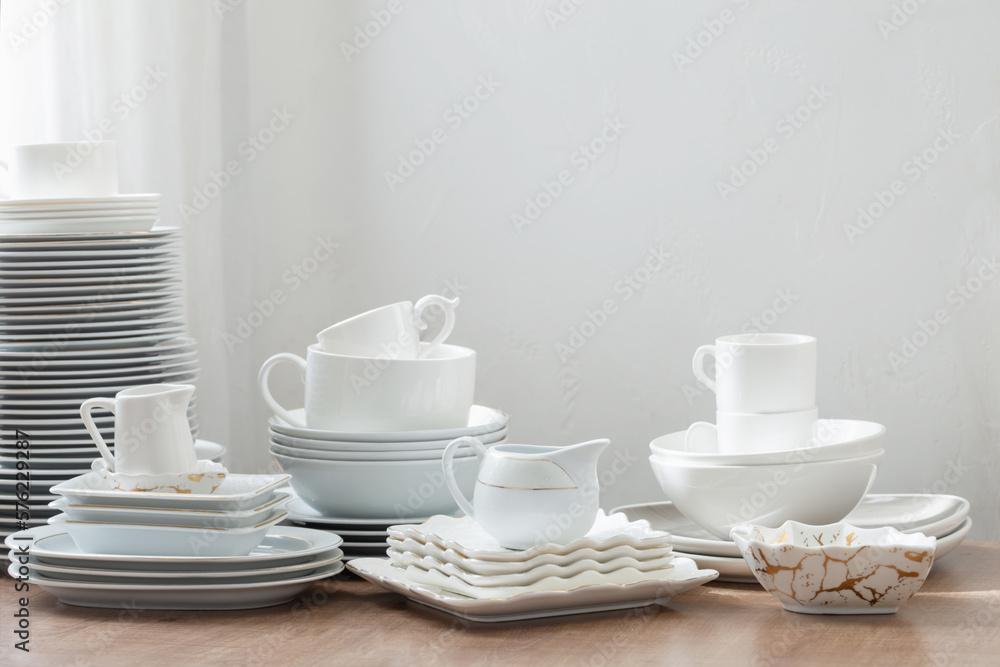 various cutlery on a wooden table against a white wall various cutlery on a wooden table against a white wall