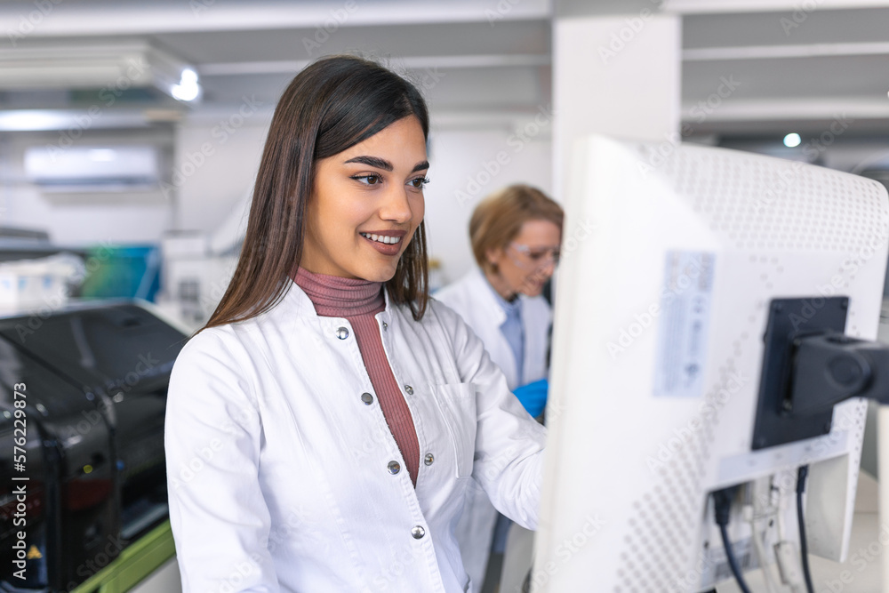 Female Scientists Programs Medical Equipment with Personal Computer. Team Of Professionals Working in Pharmaceutical Research Modern Laboratory. Female Scientists Programs Medical Equipment with Personal Computer. Team Of Professionals Working in Pharmaceutical Research Modern Laboratory.