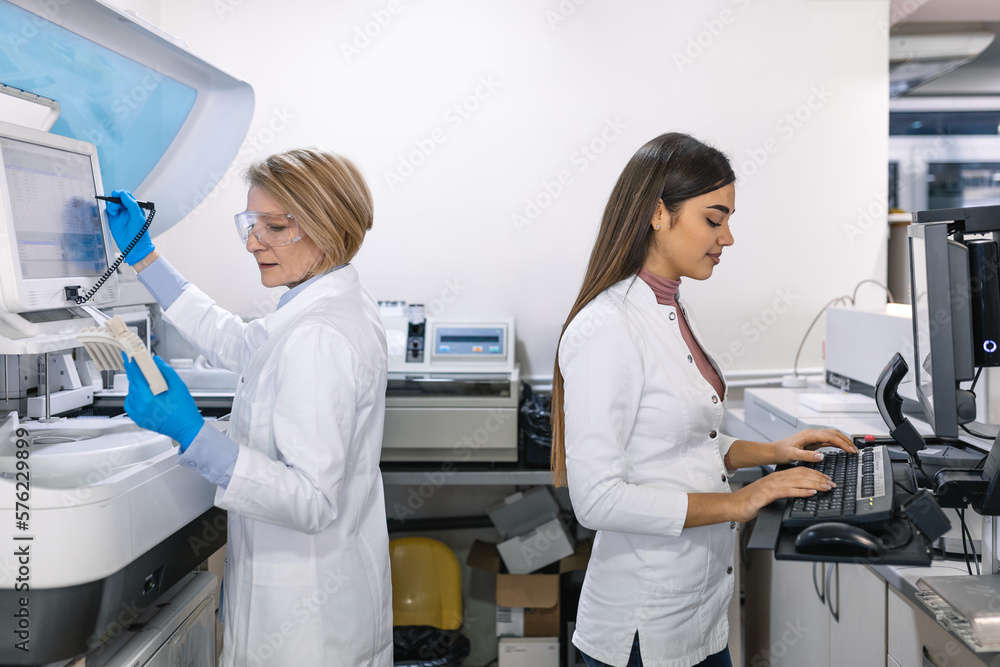 Team of Research Scientists Working On Computer, with Medical Equipment, Analyzing Blood and Genetic Material Samples with Special Machines in the Modern Laboratory. Team of Research Scientists Working On Computer, with Medical Equipment, Analyzing Blood and Genetic Material Samples with Special Machines in the Modern Laboratory.