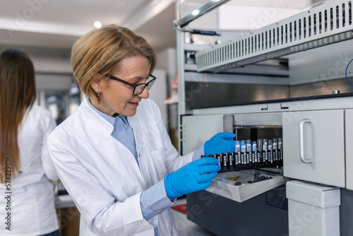 In Laboratory Female Scientist Inspects Medical Equipment Analyzing Test Tube with Blood Samples. Team of Researcher Work in Pharmaceutical Laboratory.