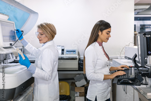 Team of Research Scientists Working On Computer  with Medical Equipment  Analyzing Blood and Genetic Material Samples with Special Machines in the Modern Laboratory.
