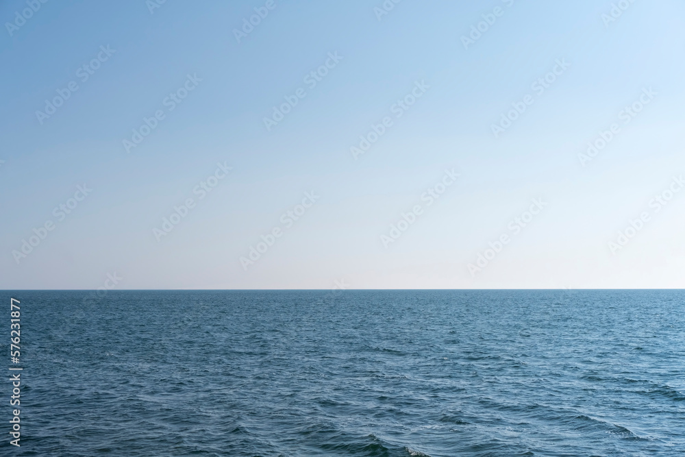 Obraz premium Aerial view of a blue sea water background and sun reflections. Aerial flying drone view. Waves water surface texture on sunny tropical ocean. Aerial photography.