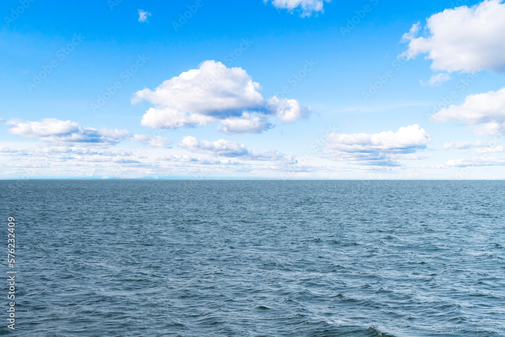 Obraz premium Aerial view of a blue sea water background and sun reflections. Aerial flying drone view. Waves water surface texture on sunny tropical ocean. Aerial photography.
