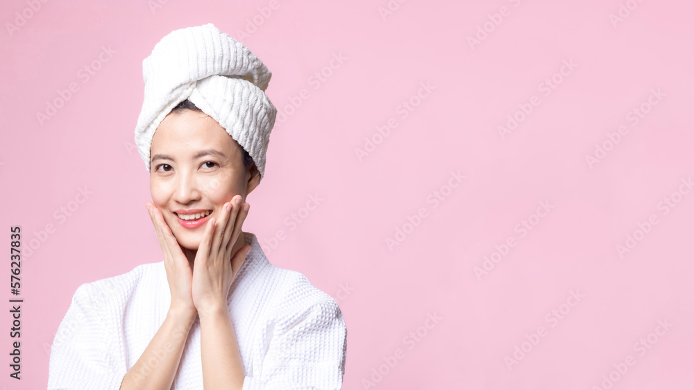 Beautiful young asian woman happy with clean face skin in towel and bathrobe, spa suit on pink background. Skincare, treatment, wellness therapy, facial care, beauty female health, cosmetology concept Beautiful young asian woman happy with clean face skin in towel and bathrobe, spa suit on pink background. Skincare, treatment, wellness therapy, facial care, beauty female health, cosmetology concept