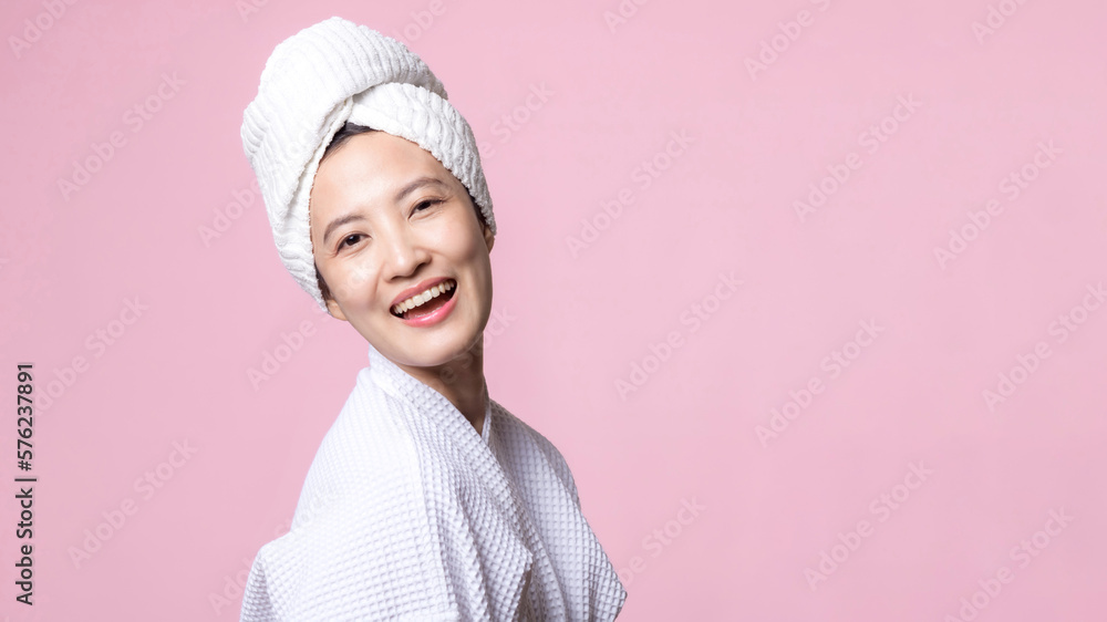 Beautiful young asian woman happy with clean face skin in towel and bathrobe, spa suit on pink background. Skincare, treatment, wellness therapy, facial care, beauty female health, cosmetology concept Beautiful young asian woman happy with clean face skin in towel and bathrobe, spa suit on pink background. Skincare, treatment, wellness therapy, facial care, beauty female health, cosmetology concept