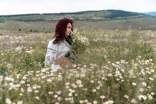 Chamomile woman. Happy curly woman in a chamomile field, dressed in a white dress.