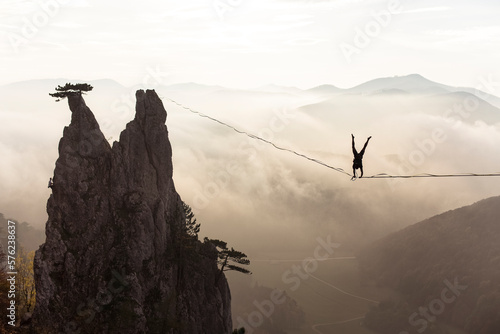 Silhouette of man doing handstand on highline high above foggy hills, Lower Austria, Austria photo