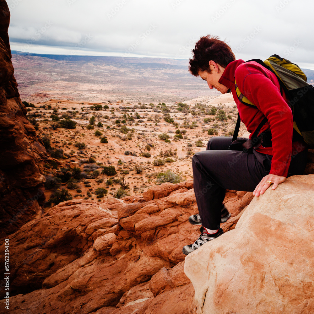 A female hiker carefully descends a steep sandstone slope. A female hiker carefully descends a steep sandstone slope.