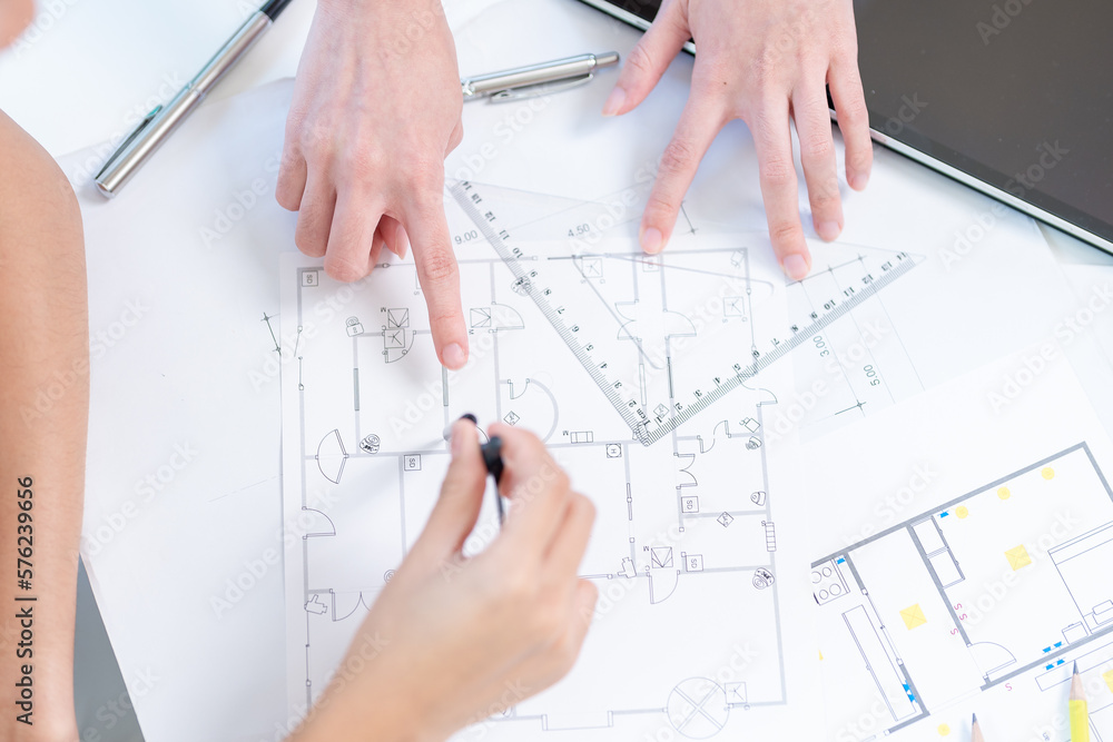 Concept of engineering consulting, Two female engineers discussing about model of building together; Two female architects are studying blueprint of building house. Concept of engineering consulting, Two female engineers discussing about model of building together; Two female architects are studying blueprint of building house.