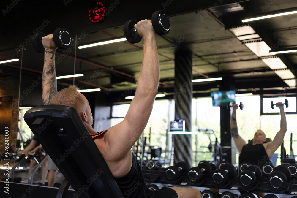 Brutal handsome athlete man bodybuilder working out training in the gym ...