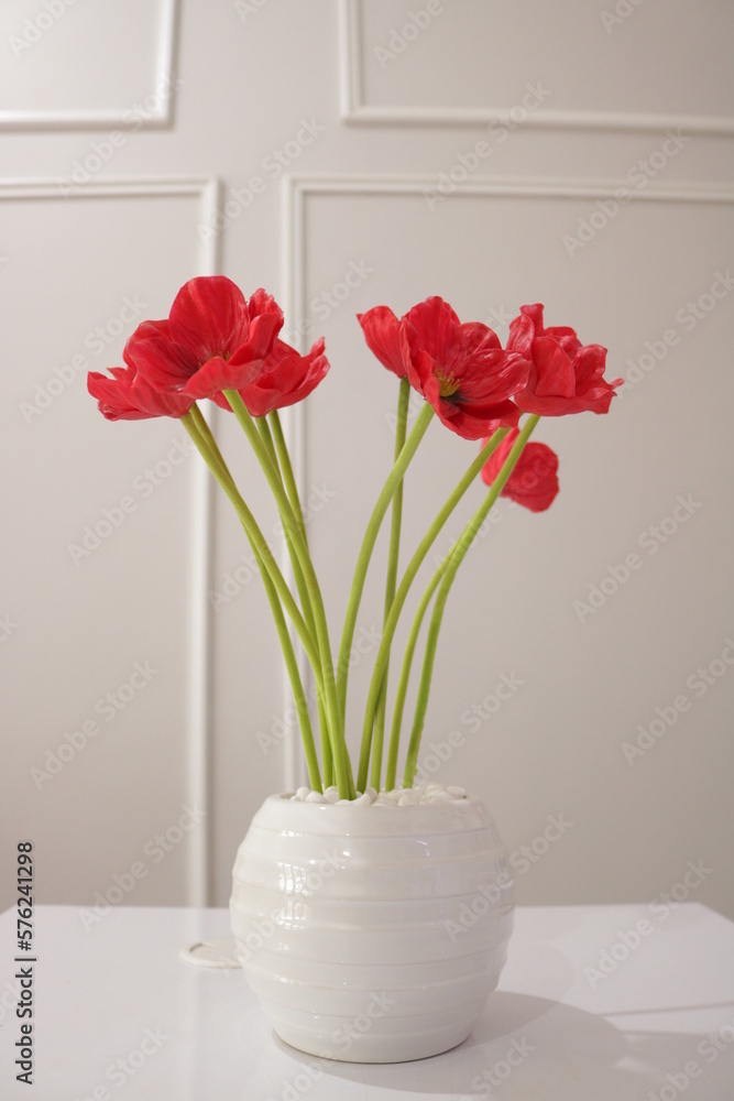 Red flowers with beautiful green stalks in a vase on the table Red flowers with beautiful green stalks in a vase on the table
