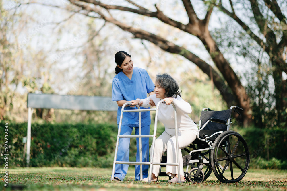 Asian careful caregiver or nurse and the happy patient in a wheelchair are walking in the garden to help and encourage and rest your mind with green nature. Asian careful caregiver or nurse and the happy patient in a wheelchair are walking in the garden to help and encourage and rest your mind with green nature.
