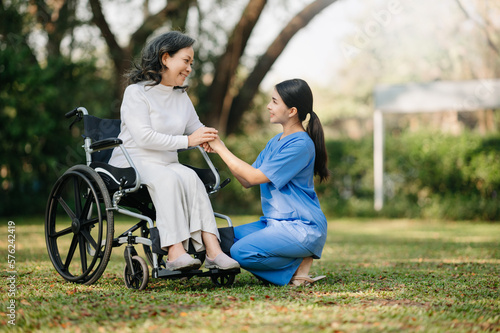 Elderly asian senior woman on wheelchair with Asian careful caregiver. Nursing home hospital garden concept. in sun light