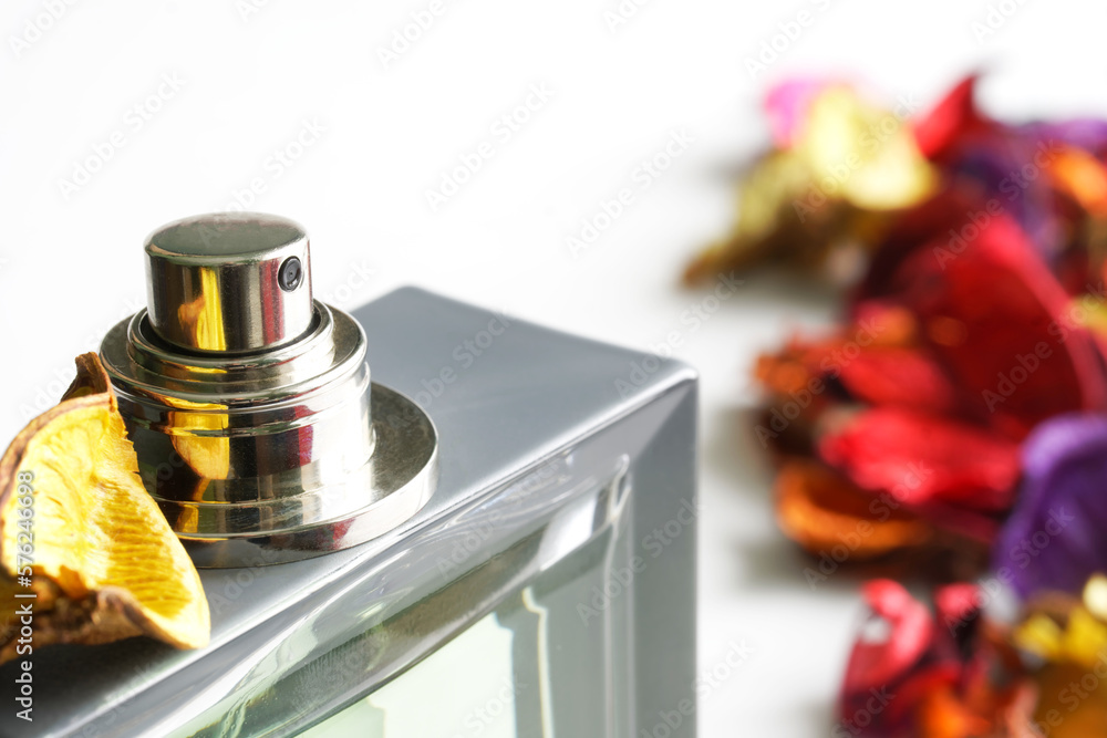 Silver used atomizer of a perfume bottle next to colorful dried flower petals. White background. Copy space. Macro. Selective focus Silver used atomizer of a perfume bottle next to colorful dried flower petals. White background. Copy space. Macro. Selective focus
