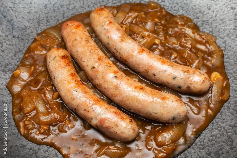 Wurst sausage in onion sauces serving on stone pan. Traditional German food. Wurst sausage in onion sauces serving on stone pan. Traditional German food.
